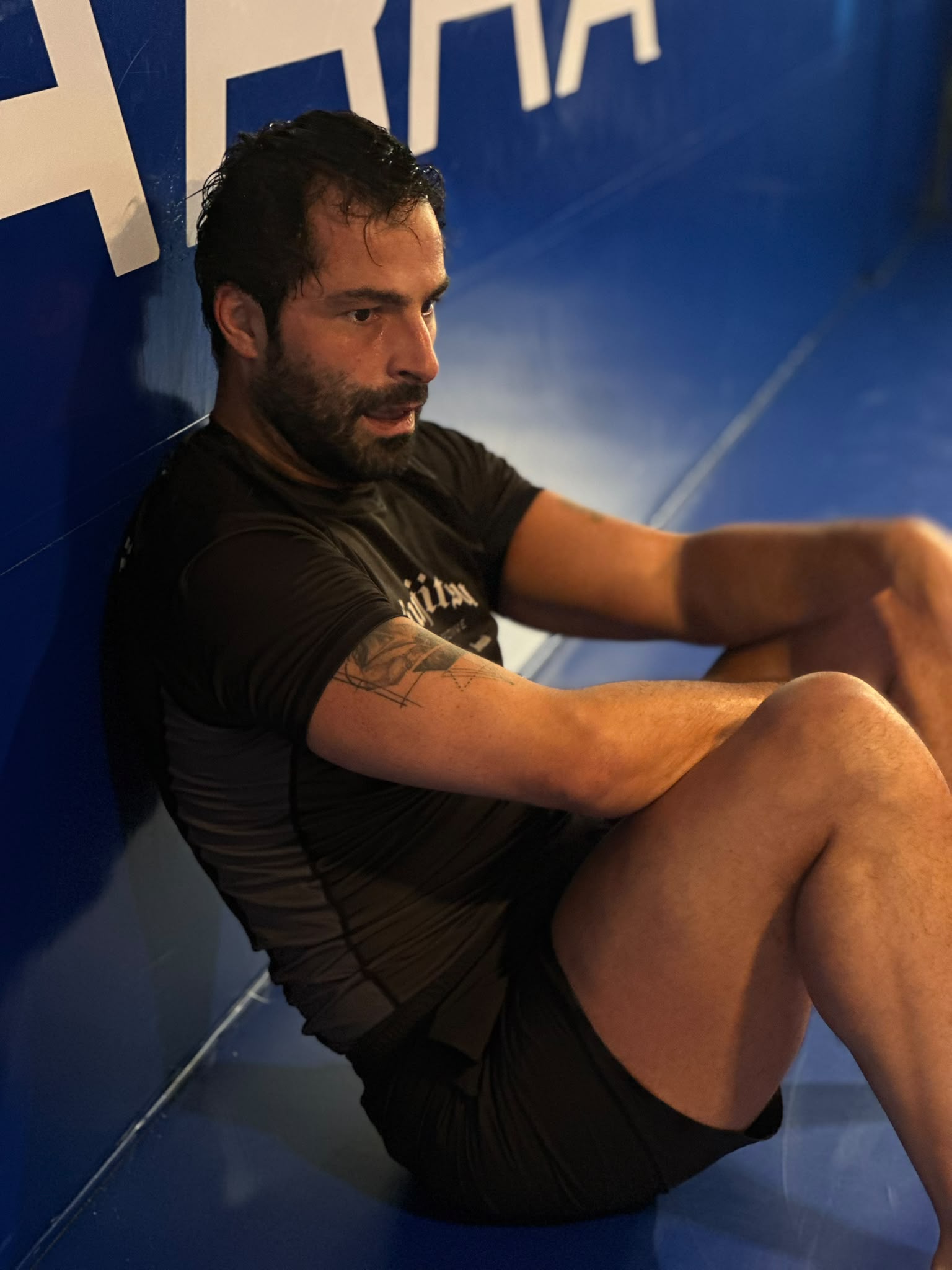 Aluno da Gracie Barra Braga descansa encostado à parede do tatame, depois de um treino intenso