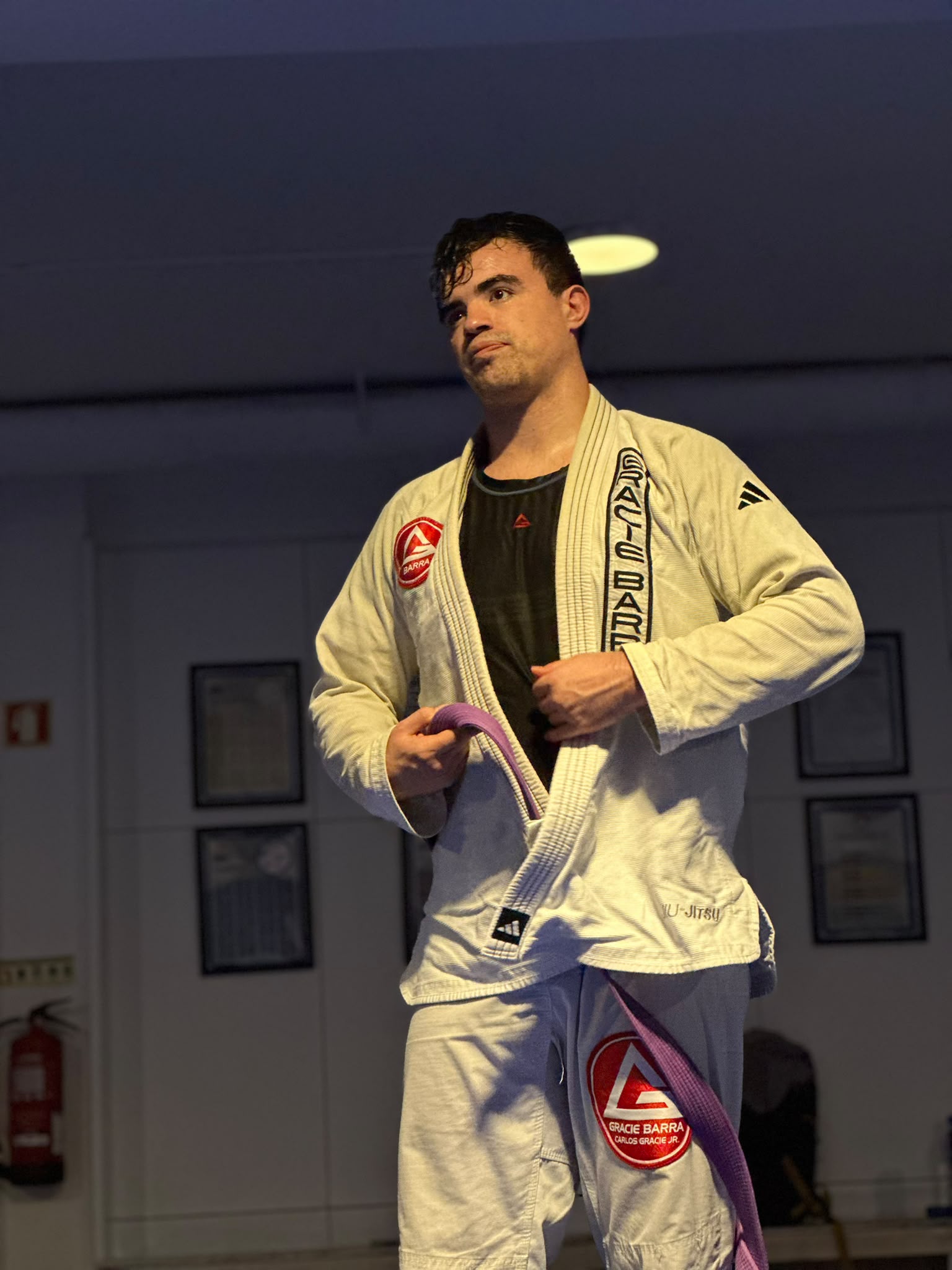 Atleta ajusta a faixa roxa depois de uma promoção na Gracie Barra Braga